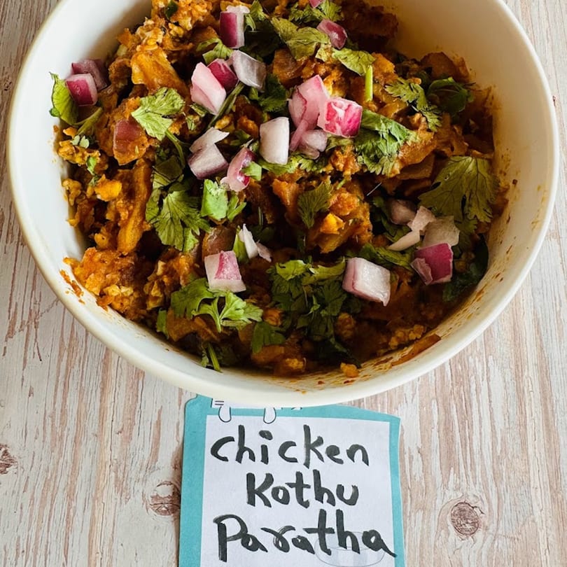 Avinya Indian Cuisine's Chicken Kothu Paratha, garnished with fresh cilantro and diced red onions.